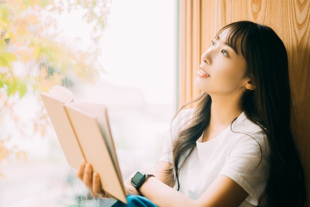 窓辺でのんびり読書をする女性