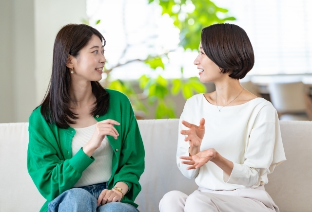 女性同士がリビングで笑顔で話をしている